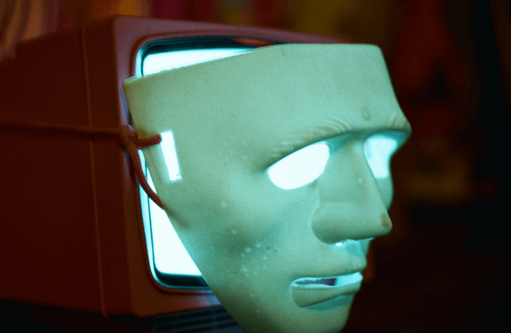 A computer screen wearing a human mask, to represent artificial voices